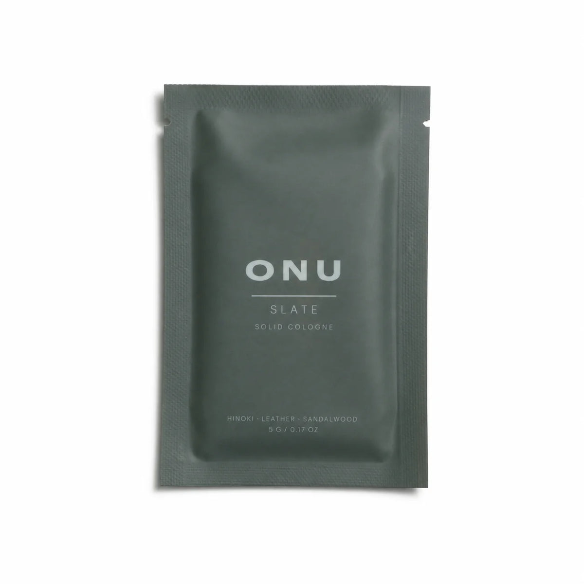 Deep green ONU SLATE solid balm cologne sachet on a clean white background.